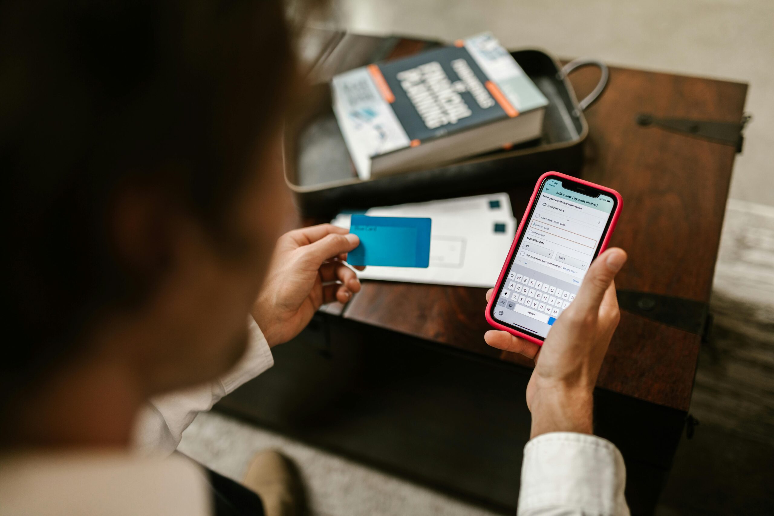 Person making an online payment using a smartphone and credit card indoors.